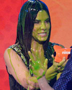 Kristen Stewart accepts the award from Sandra Bullock and Neil Patrick Harris for favorite movie actress at the 2013 Kids Choice Awards in Los Angeles, California