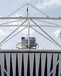 The sun is shining on the Olympic Stadium, the sky is blue and the flowers are in bloom