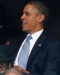 U.S. President Barack Obama (C) shares a moment with Denmark's Prime Minister Helle Thorning-Schmidt (L) as his wife, first lady Michelle Obama looks on (R) during the memorial service for late South African President Nelson Mandela at the First National Bank stadium