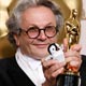 Best Animated Feature winner George Miller of Happy Feet poses with his award and a toy penguin