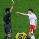 Referee Kamikawa shows Smolarek a yellow card as Tenorio lies on the pitch in Gelsenkirchen